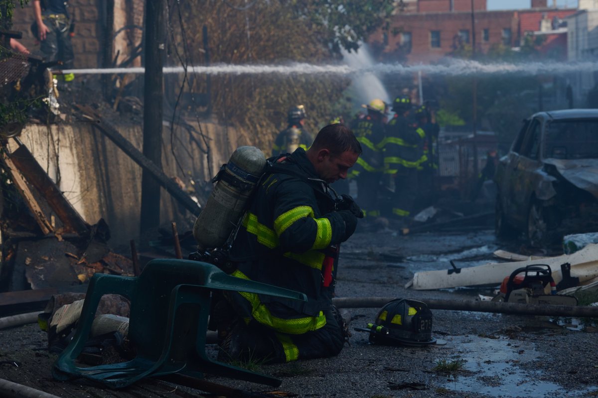 Firefighters operate on the roof as heavy flames shoot through multiple private dwellings and garages during a five-alarm fire in Queens Village.