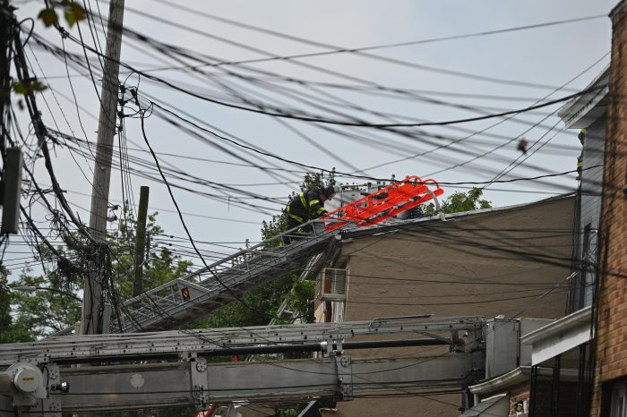 Firefighters battled a three alarm fire at 90-16 80 Street in Queens. A fireman on a ladder is seen at the fire