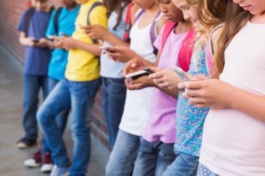 Cute pupils using mobile phone at the elementary school