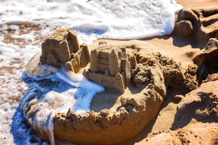 waves wash away sand castles on the beach the sea