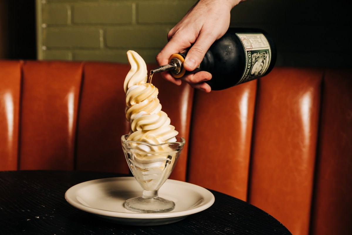 a soft serve ice cream sundae with rum being poured on top of it