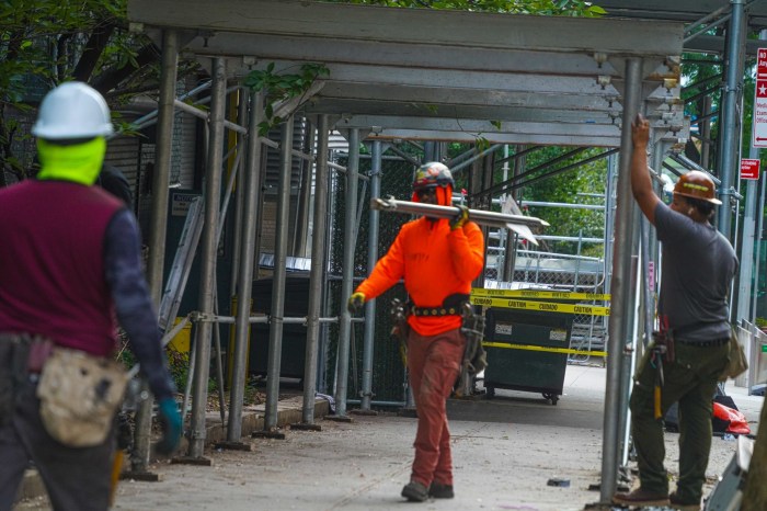 Worker removing sidewalk shed from medical examiner's office