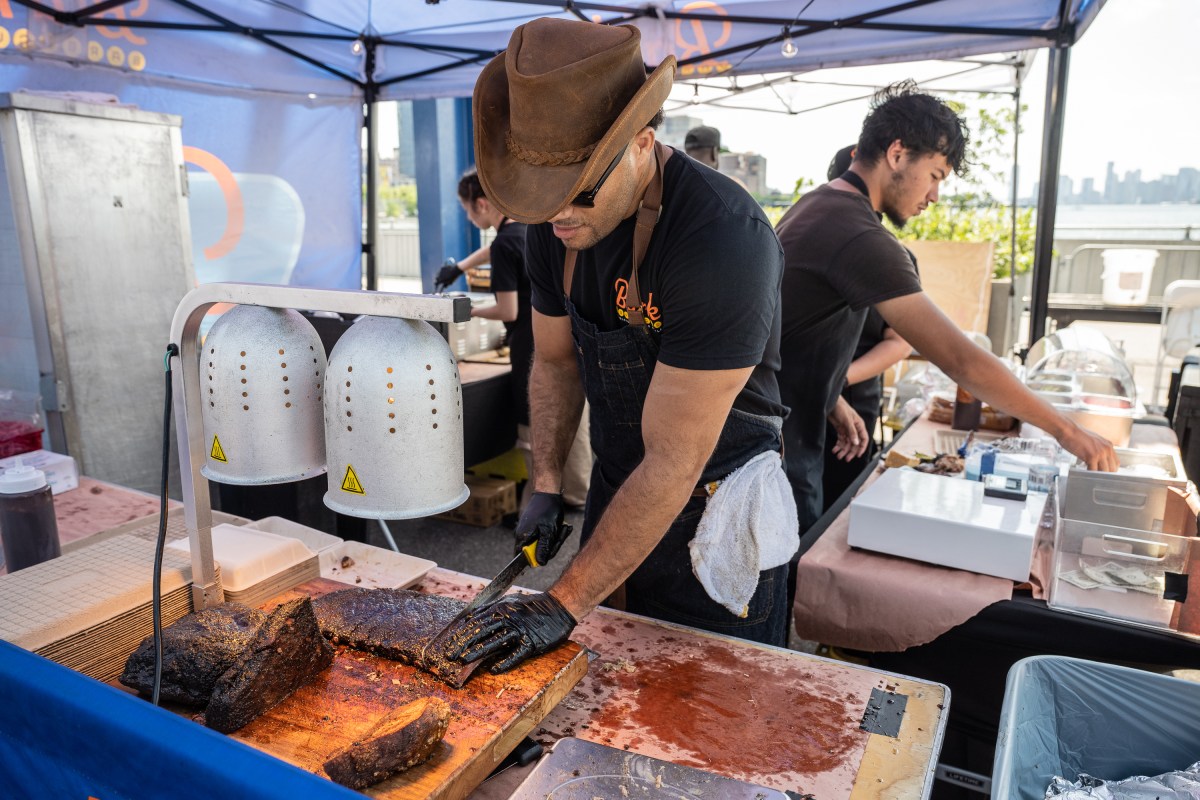 Cook cutting into barbecue brisket at Hudson River Park Blues and BBQ Festival