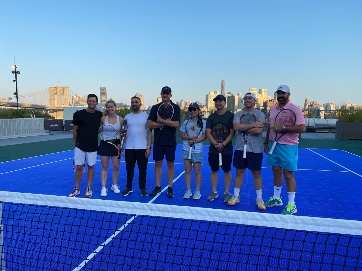 several people, at least most being US Open fans, with Andy Roddick on a tennis court at the Seaport in Lower Manhattan