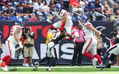 Giants tight end Theo Johnson hurdles a defender in preseason