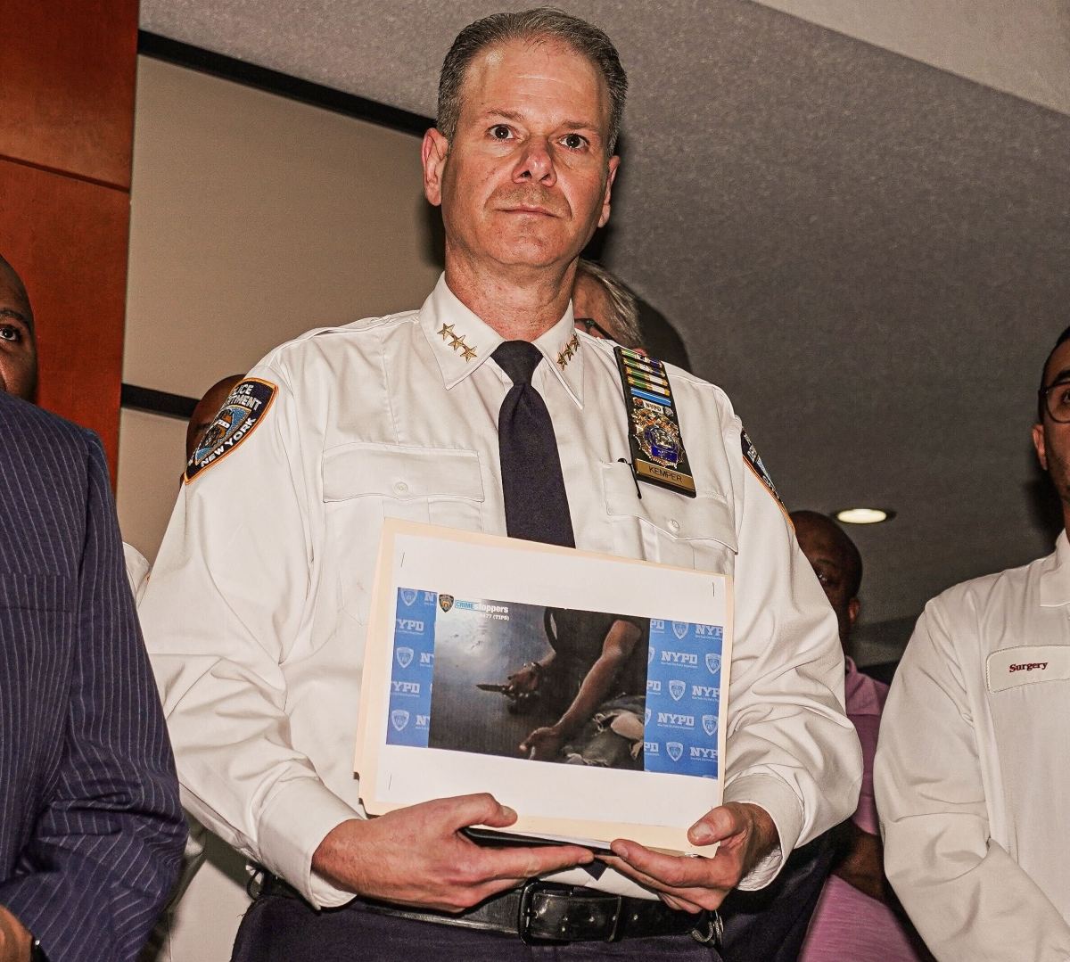 Outgoing Chief of Department Michael Kemper holds a photo of the knife recovered from the suspect