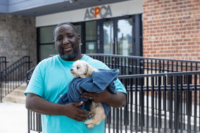 man wearing blue shirt holding a dog near ASPCA vet clinic in Queens