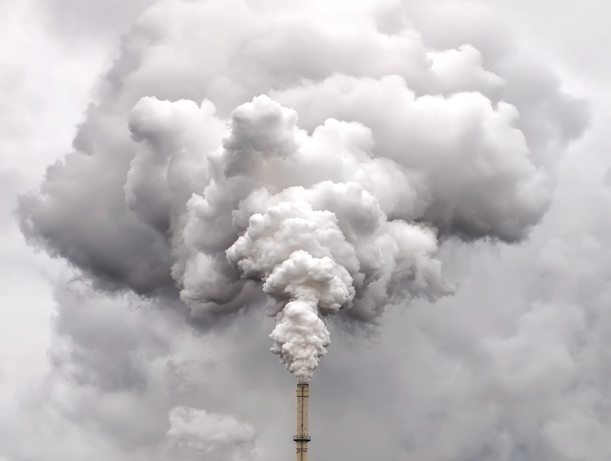 Smoke from factory pipe against dark overcast sky