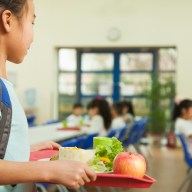 School girl holding food tray in school cafeteria