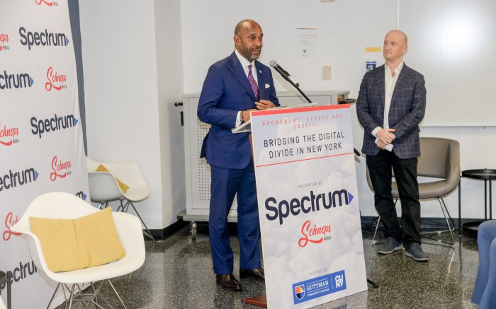 two men in next to a Spectrum sign at an event about the digital divide in NYC