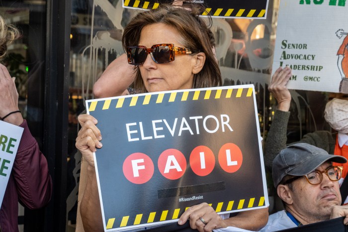 woman holding a sign that reads elevator fail