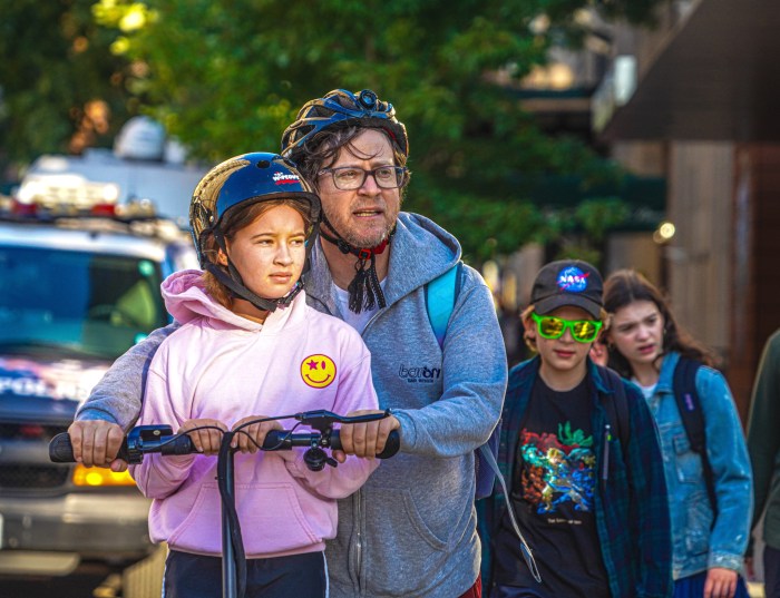 NYC kids heading back to school with one on a scooter with her father