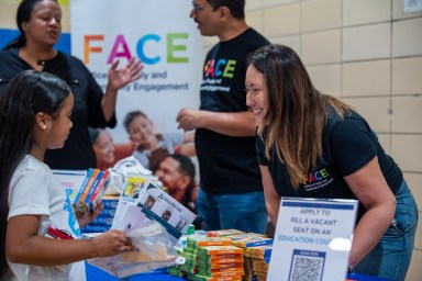 people, including DOE deputy chancellor of family and community engagement Melissa Aviles-Ramos around a table of flashcards