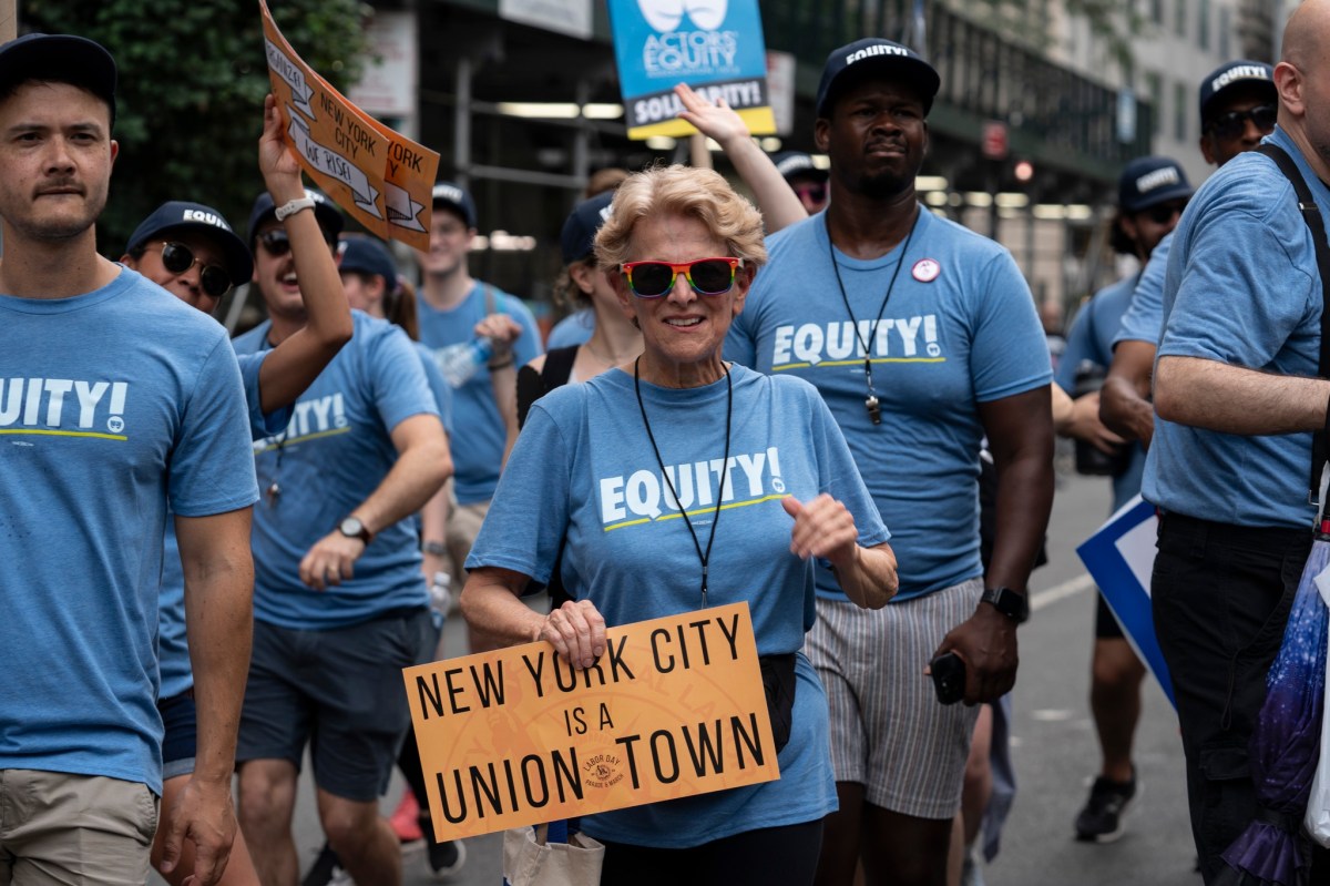 people in blue shirts participating in Labor Day Parade with a sign that says NYC is a Union Town