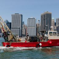 boat preparing to install oysters into NYC waters with city skyline in background