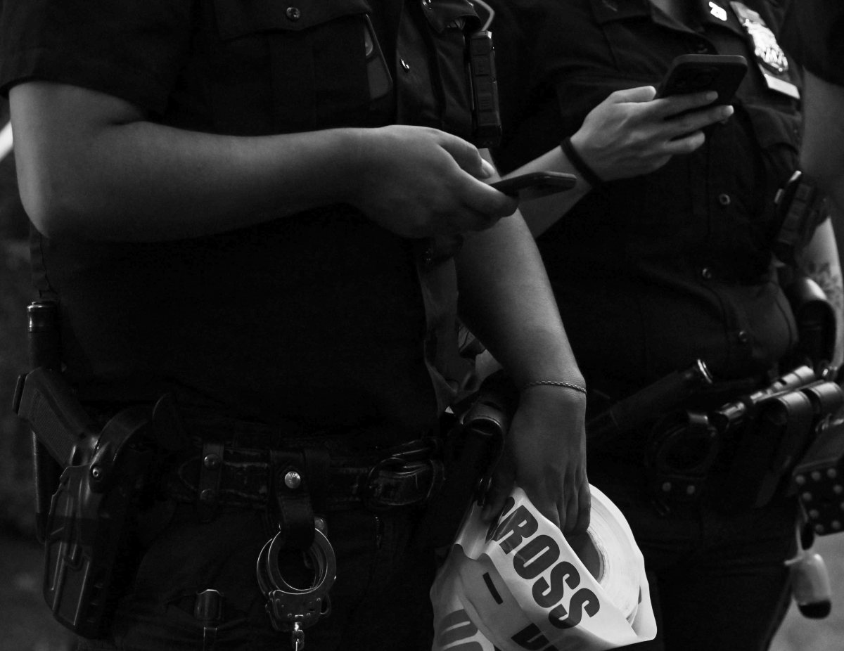 A officer holds crime scene tape at the scene of a fatal shooting in a NYCHA complex.