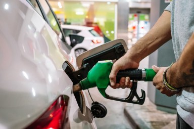 Unrecognizable male putting fuel dispenser in tank while refueling vehicle on self service gas station