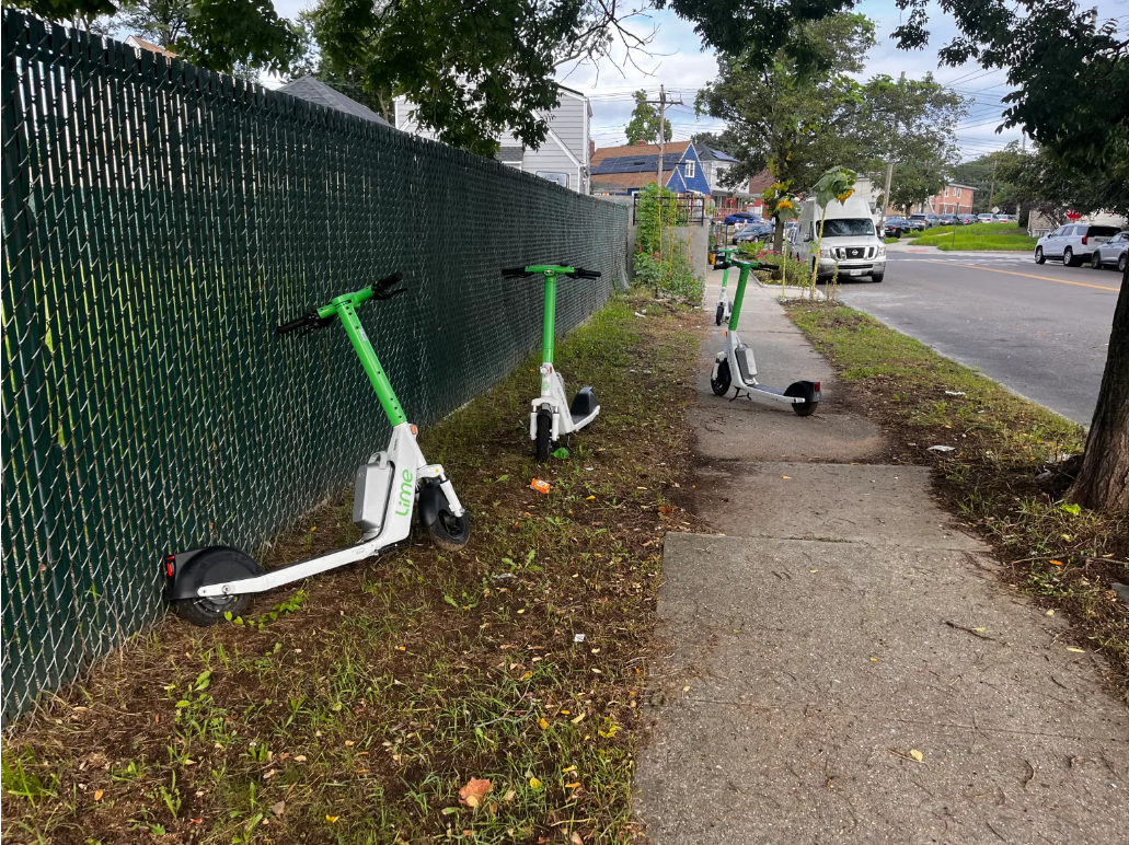 E-scooters left parked on sidewalk and grass