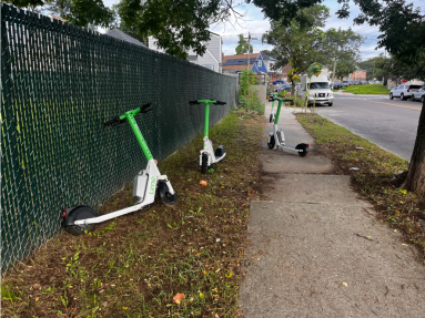 E-scooters left parked on sidewalk and grass