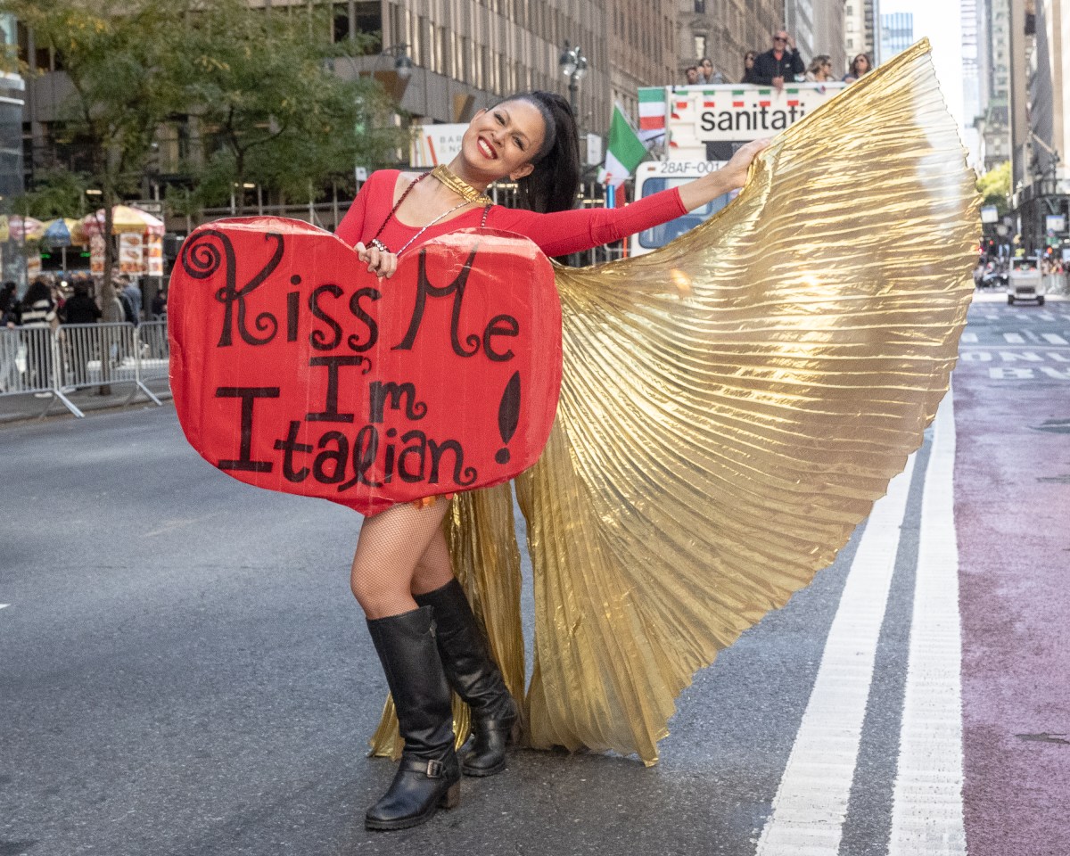 a woman holds a kiss me i'm italian sign