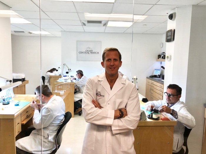 man wearing a labcoat in a watch repair workshop