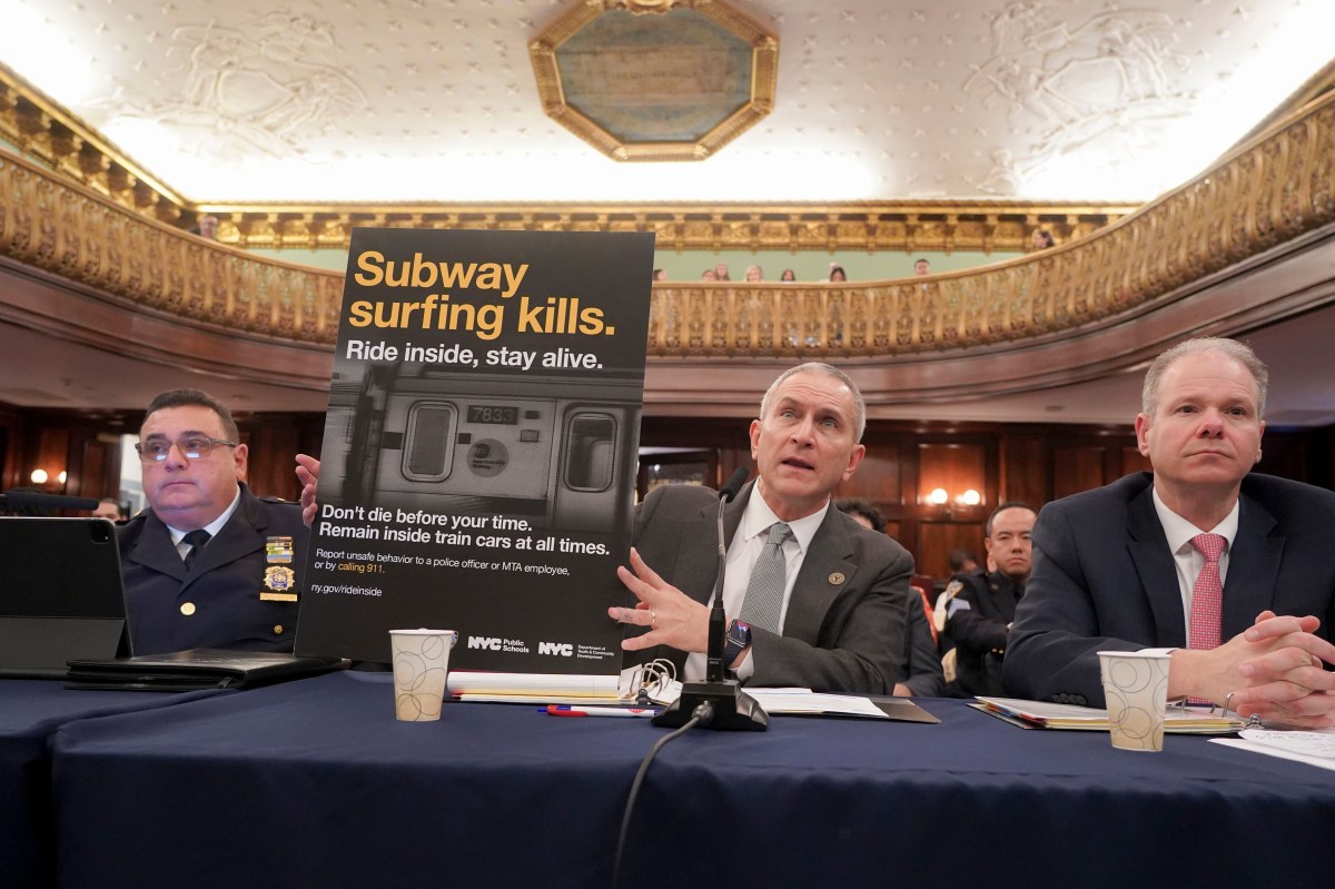 MTA Special Counsel Jeremy Feigelson (c.) holds up a "Subway surfing kills" sign at the Nov. 18 City Council hearing, flanked by NYPD Chief of Transit Joseph Gulotta (l.) and MTA Chief Security Officer Michael Kemper.