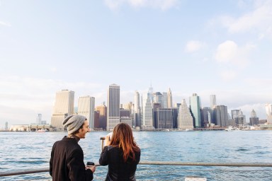 Rear view of young couple looking at Manhattan skyline from Brooklyn