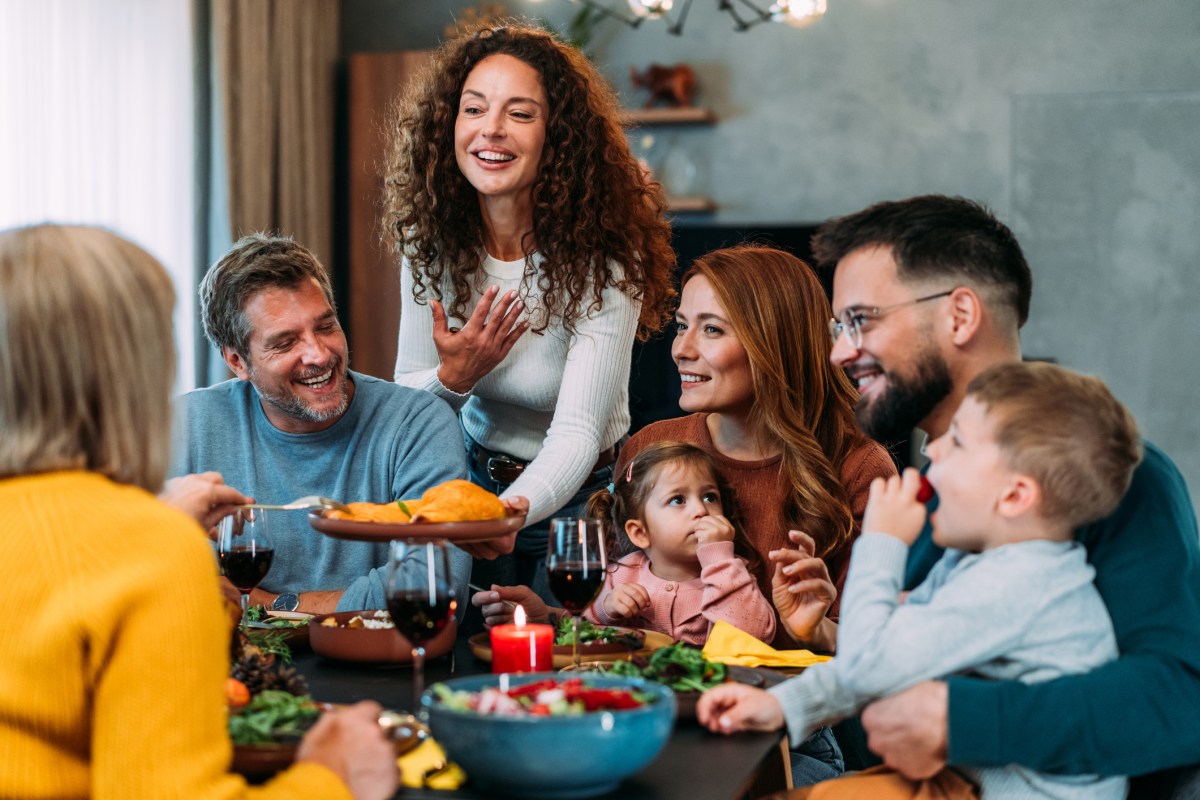 Shot of happy multi-generation family gathering for Thanksgiving meal at dining table. Cheerful family having dinner or lunch with roast turkey.