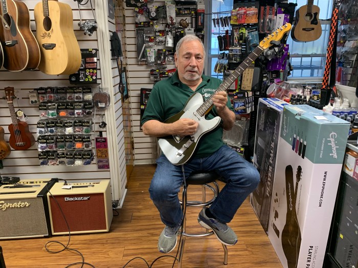 man holding a guitar in a music store