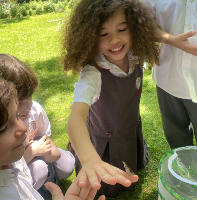 a butterfly lands on a child's hand in a park