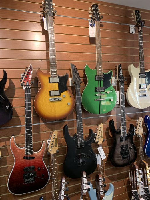 several guitars hanging on a wall in a music store in NYC