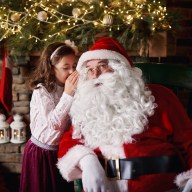 Young girl visiting Santa, whispering into Santas ear