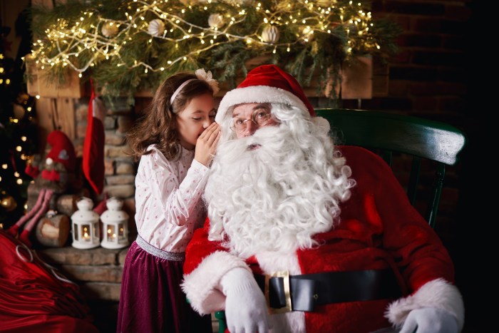 Young girl visiting Santa, whispering into Santas ear