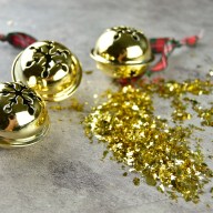 Golden jingle bell in a table with golden confetti, close-up