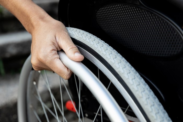 Close-up of a woman's hand on the wheel of a wheelchair. Concept of reduced mobility