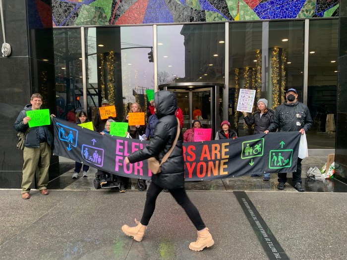 a group of people outside  a building protesting for more accessibility at subway stations in NYC