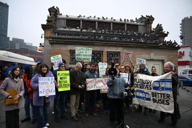 people outside near a bus stop rallying for better bus service in Brooklyn