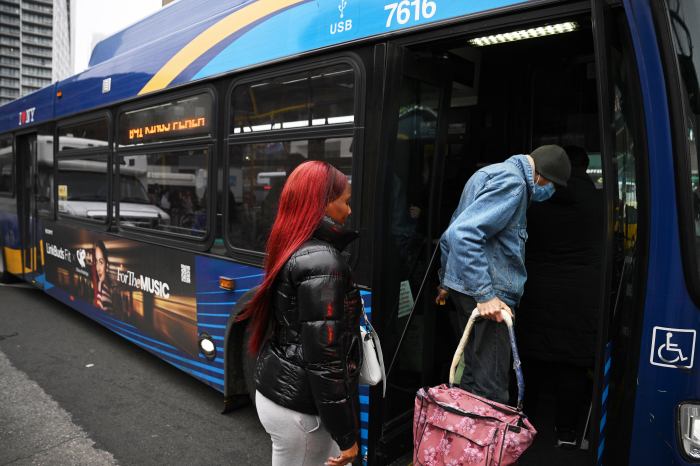 Passengers board a bus in Brooklyn during the day