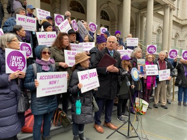 people on steps with signs supporting registration for e-bikes in NYC