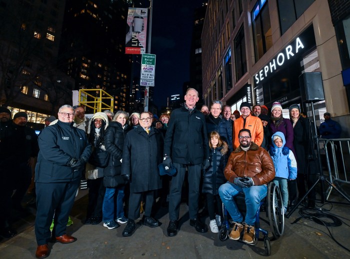 group of people next to a congestion pricing sign at night