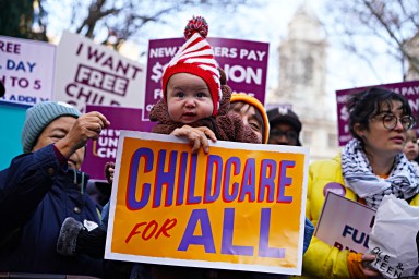 Child and parent holding up sign seeking universal childcare