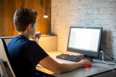 Teenage boy reading a school task on his computer.