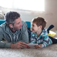 Smiling boy listening music with his father