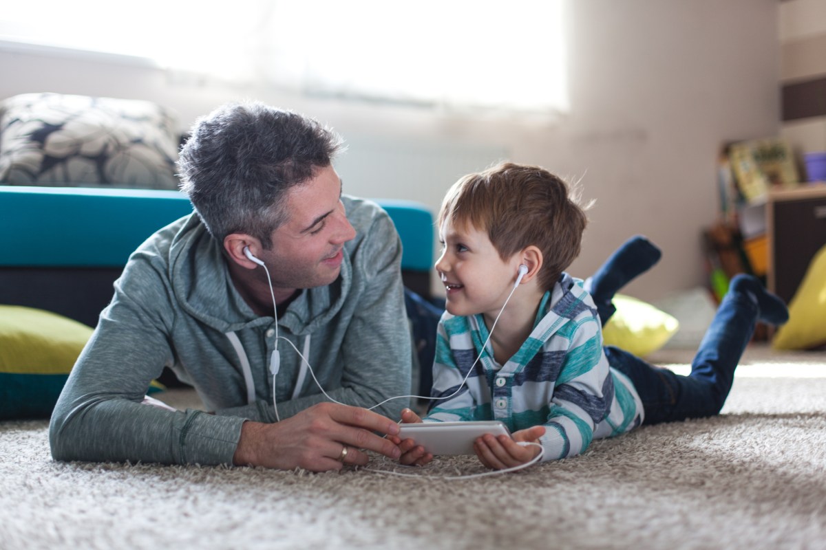 Smiling boy listening music with his father