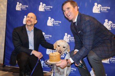 Guiding Eyes for the Blind CEO Thomas Panek (left) celebrated his one-year anniversary with his guide dog, Ten, with Eli Manning (right).