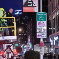 two people unveiling a congestion pricing sign at night