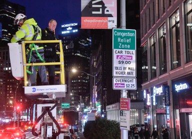 two people unveiling a congestion pricing sign at night