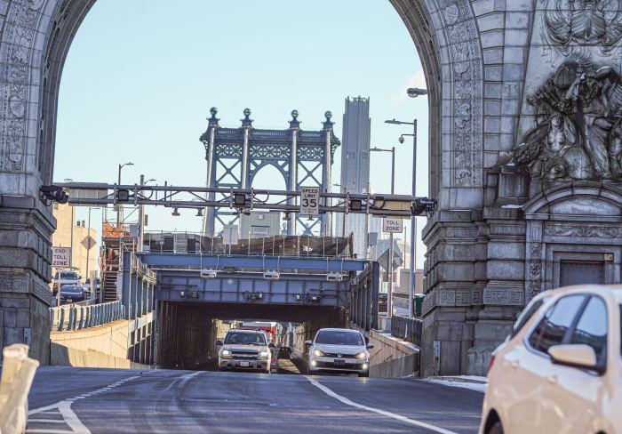 Congestion pricing cars travel through grand arch of Manhattan Bridge