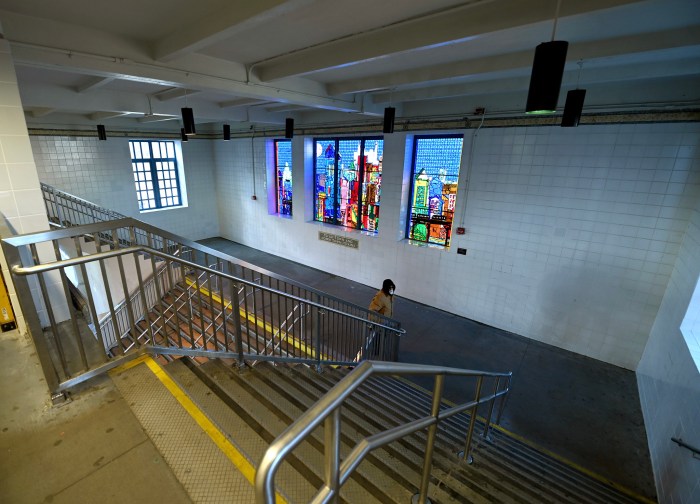 person walking in side a large Bronx subway station that has stairs