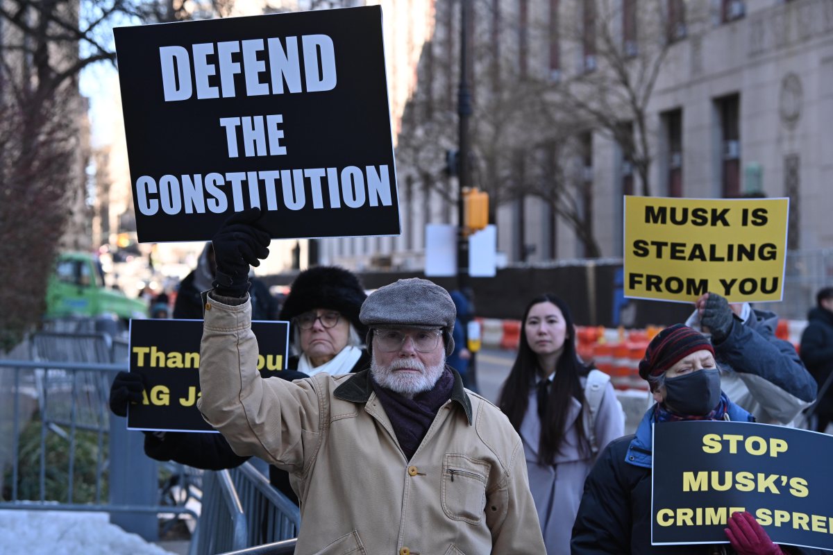 a man holds a sign that says "defend the constitution"